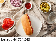 Тарелка с вкусным хот-догом и овощами на белом столе. Стоковое фото, фотограф Pixel_shot / Фотобанк Лори