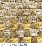 Close-up of a woven fabric made from natural fibers. The material is made in warm, beige and golden shades, creating a natural and organic look. The fibers are intertwined in a checkerboard pattern, forming a dense and durable structure. The texture is rough, but at the same time aesthetic, with noticeable villi, which emphasizes the naturalness of the material. This type of weaving is often used to create carpets, mats, furniture or decorative elements in eco-style. Стоковое AI-изображение, AI-художник Анна Кривицкая / Фотобанк Лори