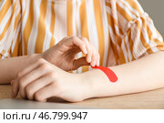 Молодая женщина накладывает пластырь дома, крупным планом. Стоковое фото, фотограф Pixel_shot / Фотобанк Лори