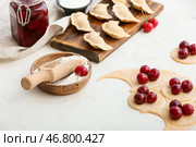 Деревянная доска с клецками из сырой вишни, свежим тестом и мукой на столе на кухне. Стоковое фото, фотограф Pixel_shot / Фотобанк Лори