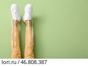 Ноги женщины с расстегнутыми шнурками на цветном фоне. Стоковое фото, фотограф Pixel_shot / Фотобанк Лори