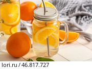 Банка Мэйсона и стакан с ароматизированной водой с кусочками апельсина на белом плиточном столе. Стоковое фото, фотограф Pixel_shot / Фотобанк Лори
