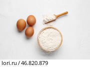 Деревянная чаша с пшеничной мукой, черпаком и яйцами на белом фоне. Стоковое фото, фотограф Pixel_shot / Фотобанк Лори