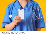 Женский медицинский интерн с бейджем на желтом фоне, крупным планом. Стоковое фото, фотограф Pixel_shot / Фотобанк Лори