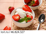 Миска ванильного мороженого с клубникой, мятой и ложкой на бежевом плиточном столе. Стоковое фото, фотограф Pixel_shot / Фотобанк Лори