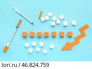 ИНСУЛИН с шприцами, сахаром и стрелкой, направленной вниз, на синем фоне. Стоковое фото, фотограф Pixel_shot / Фотобанк Лори