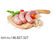 Доска с сырыми свежими колбасами, помидорами и специями на белом фоне. Стоковое фото, фотограф Pixel_shot / Фотобанк Лори