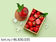 Стакан с водой с добавлением фруктов и деревянная коробка со свежими клубникой на зеленом фоне. Стоковое фото, фотограф Pixel_shot / Фотобанк Лори