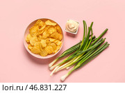 Миска вкусной сметаны с зеленым луком и картофельными чипсами на розовом фоне. Стоковое фото, фотограф Pixel_shot / Фотобанк Лори