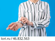 Зрелая женщина закатывает рукав на светло-голубом фоне, крупным планом. Стоковое фото, фотограф Pixel_shot / Фотобанк Лори