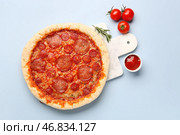 Доска с вкусной пиццей пепперони, помидорами и соусом на синем фоне. Стоковое фото, фотограф Pixel_shot / Фотобанк Лори