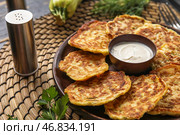 Тарелка вкусных кабачковых оладий с сметаной на столе. Стоковое фото, фотограф Pixel_shot / Фотобанк Лори