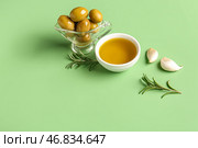 Соусница с спелыми оливками и миска с маслом на зеленом фоне. Стоковое фото, фотограф Pixel_shot / Фотобанк Лори