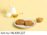 Тарелка с тостами с арахисовым маслом и миска с медом на желтом фоне. Стоковое фото, фотограф Pixel_shot / Фотобанк Лори