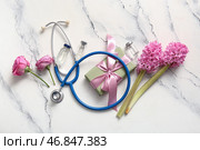 Стетоскоп с цветами, ампулы и подарочная коробка ко Дню медсестры на белом фоне с эффектом потертости. Стоковое фото, фотограф Pixel_shot / Фотобанк Лори