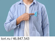 Молодой человек указывает на голубую ленту на цветном фоне, крупным планом. Концепция осведомленности о раке простаты. Стоковое фото, фотограф Pixel_shot / Фотобанк Лори