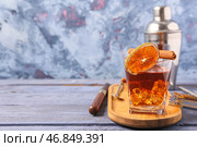 Доска с бокалом вкусного коктейля "Олд-фэшнед" и кусочком апельсина на синем деревянном столе. Стоковое фото, фотограф Pixel_shot / Фотобанк Лори