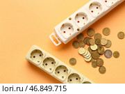 Розетки с монетами на оранжевом фоне. Концепция счетов за электроэнергию. Стоковое фото, фотограф Pixel_shot / Фотобанк Лори