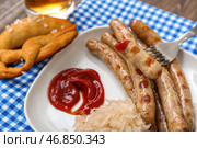 Тарелка с вкусными баварскими колбасами, соусом и квашеной капустой на столе. Празднование Октоберфеста. Стоковое фото, фотограф Pixel_shot / Фотобанк Лори