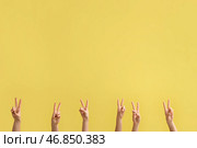Женские руки, показывающие жест мира на желтом фоне. Стоковое фото, фотограф Pixel_shot / Фотобанк Лори