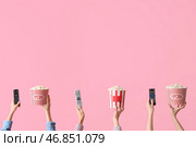Руки с ведрами попкорна и пультами от телевизора на розовом фоне. Стоковое фото, фотограф Pixel_shot / Фотобанк Лори