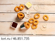 Металлические ведра с жареными хлебными кольцами луковицы в панировке и различными соусами на белом деревянном фоне. Стоковое фото, фотограф Pixel_shot / Фотобанк Лори