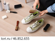 Женщина-шорник со стильными кедами и чистящими средствами за деревянным столом. Стоковое фото, фотограф Pixel_shot / Фотобанк Лори