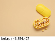 Контейнер с желтыми таблетками на цветном фоне. Стоковое фото, фотограф Pixel_shot / Фотобанк Лори