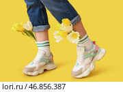 Ноги красивой молодой женщины в кедах с тюльпанами на желтом фоне. Стоковое фото, фотограф Pixel_shot / Фотобанк Лори