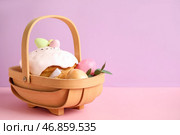 Композиция с вкусным пасхальным кексом и покрашенными яйцами в деревянной корзине на цветном фоне. Стоковое фото, фотограф Pixel_shot / Фотобанк Лори