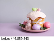 Композиция с вкусным пасхальным кексом, фарфоровым кроликом и раскрашенными яйцами в тарелке на цветном фоне. Стоковое фото, фотограф Pixel_shot / Фотобанк Лори