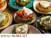 Тарелки с вкусными яйцами Бенедикт на деревянном фоне. Стоковое фото, фотограф Pixel_shot / Фотобанк Лори