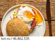 Тарелка с вкусным яйцом Бенедикт на деревянном фоне, крупным планом. Стоковое фото, фотограф Pixel_shot / Фотобанк Лори