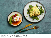 Тарелки с вкусными яйцами Бенедикт на сером гранжевом столе. Стоковое фото, фотограф Pixel_shot / Фотобанк Лори