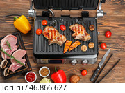 Современный электрический гриль с вкусными стейками и овощами на деревянном фоне. Стоковое фото, фотограф Pixel_shot / Фотобанк Лори