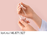 Женщина с бутылкой масла для кутикулы возле цветной стены. Стоковое фото, фотограф Pixel_shot / Фотобанк Лори