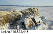 Aerial view of a huge frozen lake covered by snow with a cliff rising up through ice. Стоковое фото, фотограф David Kashakhi / Фотобанк Лори