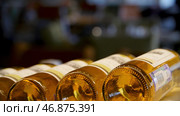 Blurred bottles of white and rose wine are nicely laid out in a row on a shelf in a large supermarket. Стоковое фото, фотограф David Kashakhi / Фотобанк Лори