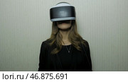 Woman using finger to touch on imaginary panel viewing on VR device against white wall. Стоковое фото, фотограф David Kashakhi / Фотобанк Лори