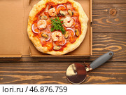 Картонная коробка с вкусной пиццей из морепродуктов на деревянном фоне. Стоковое фото, фотограф Pixel_shot / Фотобанк Лори