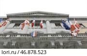 The onsulate house with country flags waving in the wind, bottom view. Стоковое фото, фотограф David Kashakhi / Фотобанк Лори