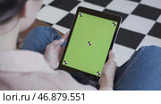 Young brunette woman watching her tablet with green screen on black and white floor background. Стоковое фото, фотограф David Kashakhi / Фотобанк Лори