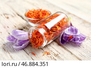 Перевернутая банка и чаша со сушеными нитями шафрана с крокусами на белом деревянном столе. Стоковое фото, фотограф Pixel_shot / Фотобанк Лори