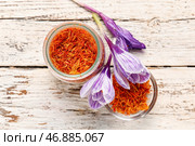 Банка и чаша с сушенными нитями шафрана и крокусами на белом деревянном столе. Стоковое фото, фотограф Pixel_shot / Фотобанк Лори