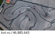 Racers traning or competing on the karting track in protective uniform and helmet, aerial view. Стоковое фото, фотограф David Kashakhi / Фотобанк Лори