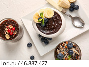 Стаканы и миска с вкусным шоколадным пудингом, ягодами, орехами и бананом на белом столе. Стоковое фото, фотограф Pixel_shot / Фотобанк Лори