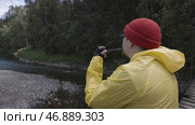 Side view of the bearded man in warm red hat smoking pipe in the wild forest in the autumn. Стоковое фото, фотограф David Kashakhi / Фотобанк Лори