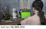 Over the shoulder shot of a woman typing on a computer laptop with a chromakey green screen. Стоковое фото, фотограф David Kashakhi / Фотобанк Лори