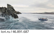 Aerial view of a hovercraft going into a skid on icy water surface around the rock cliff. Стоковое фото, фотограф David Kashakhi / Фотобанк Лори