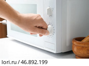 Женщина регулирует современную микроволновую печь на кухне, крупным планом. Стоковое фото, фотограф Pixel_shot / Фотобанк Лори